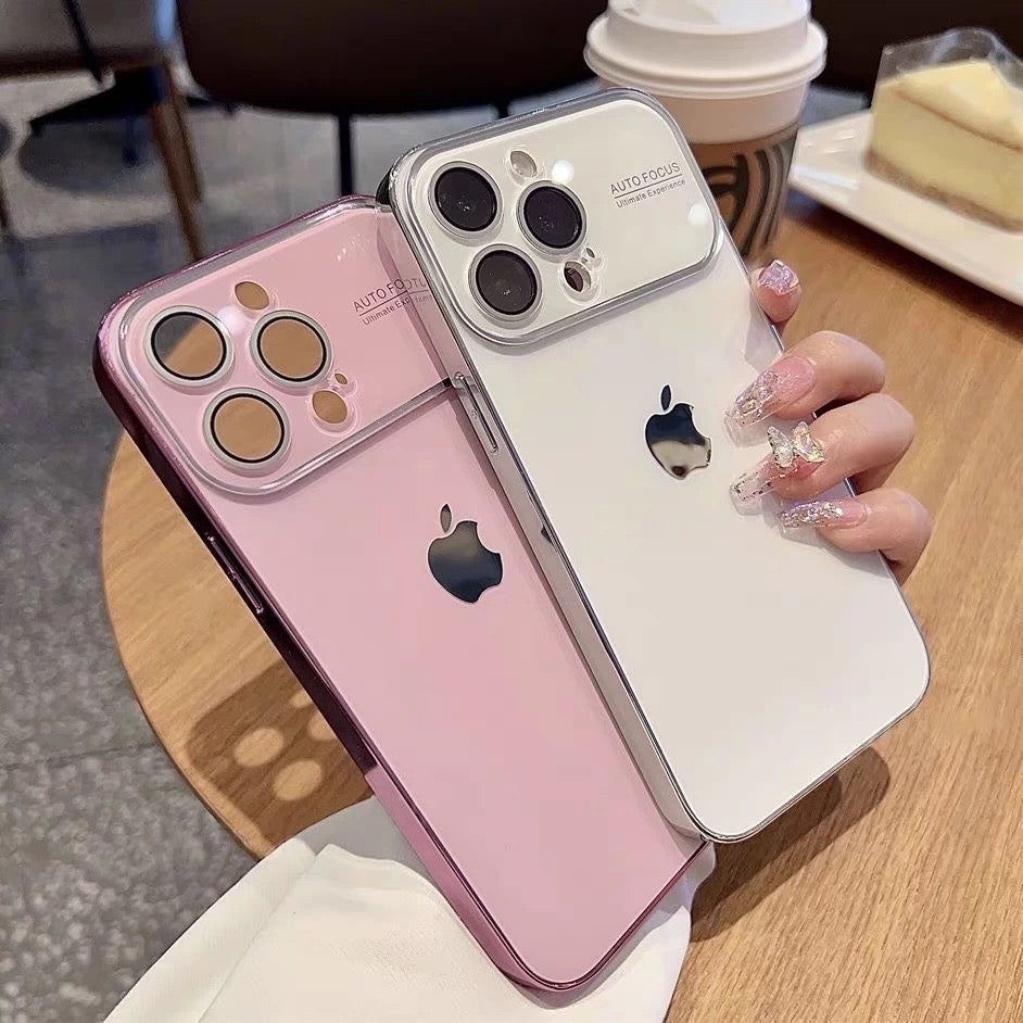 Two iPhones, one pink and one white, held by a hand with a blurred background of a cafe setting.