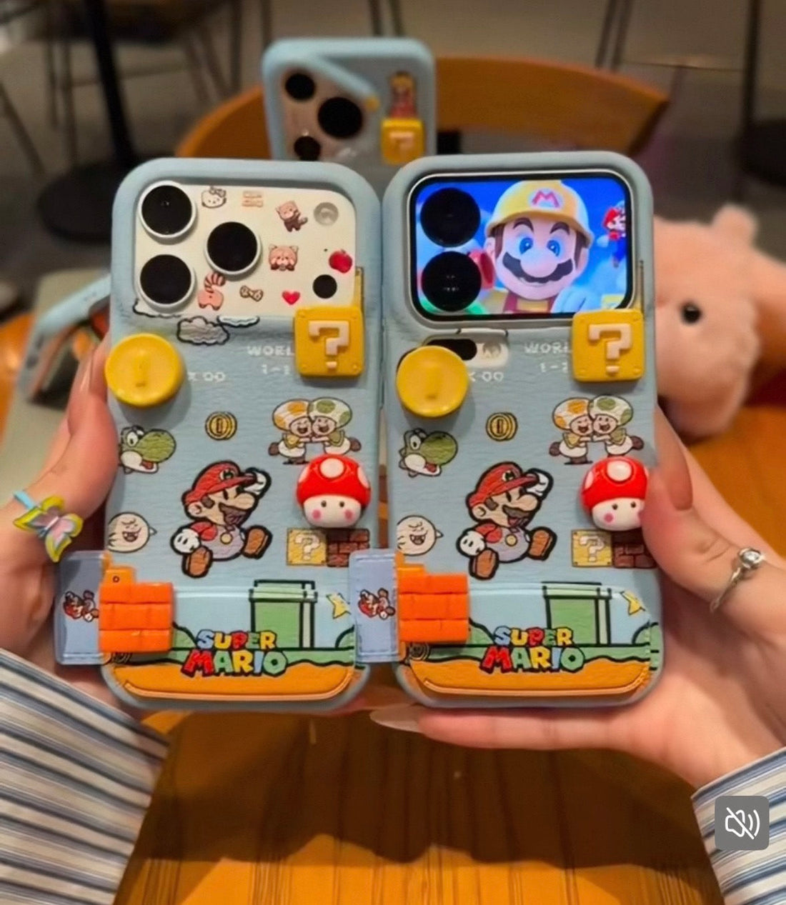 Two phone cases with Super Mario design held by a person.